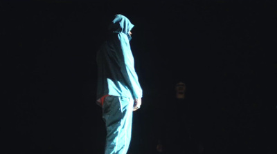 a person in a hooded jacket standing in the dark