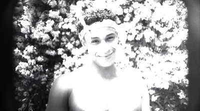 a man standing in front of a bush of flowers