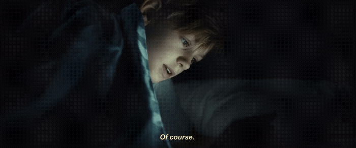 a boy is hiding behind a blanket in the dark