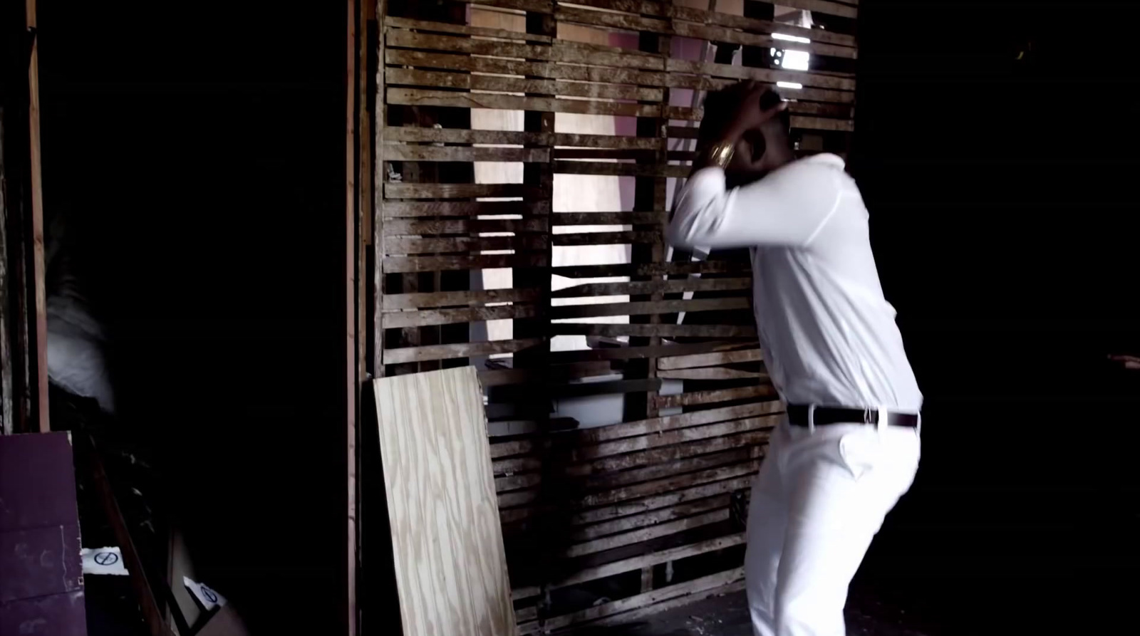 a man standing next to a wooden wall