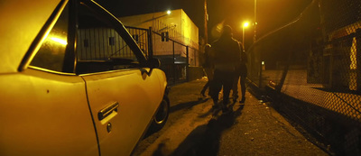 a couple of people walking down a street at night