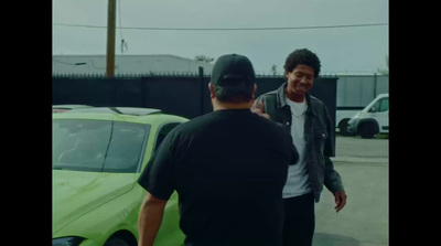 a man standing next to a green car talking to another man