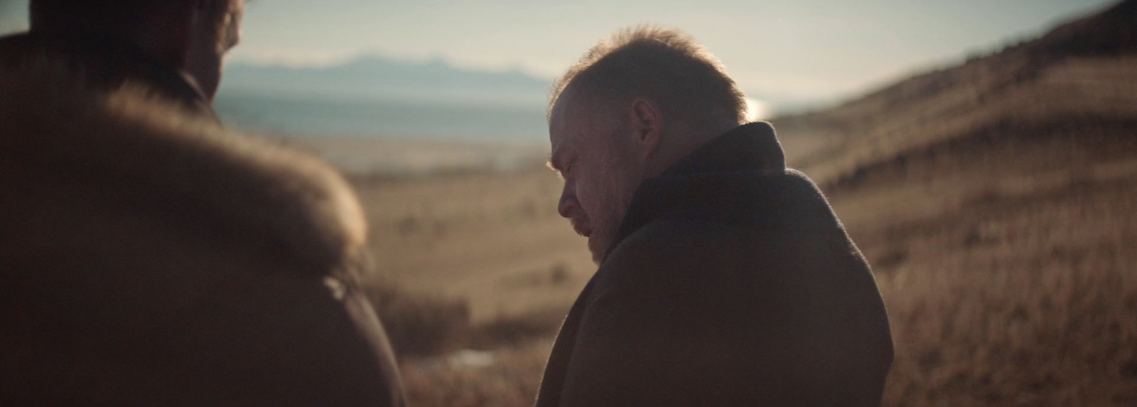 a man in a hooded jacket standing in a field