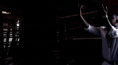 a man in a white shirt and tie standing in a dark room