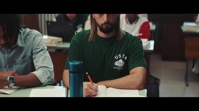 a man sitting at a desk writing on a piece of paper