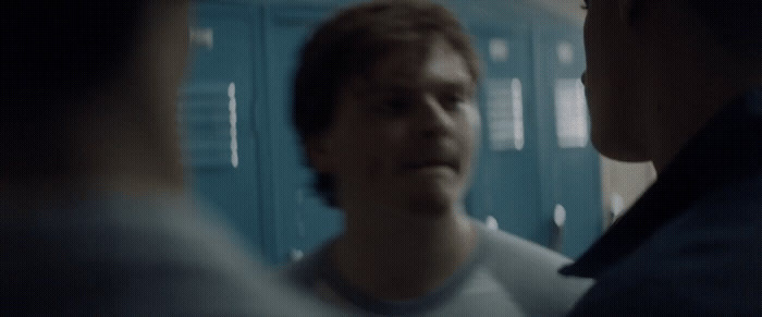 a man standing in front of lockers talking to another man