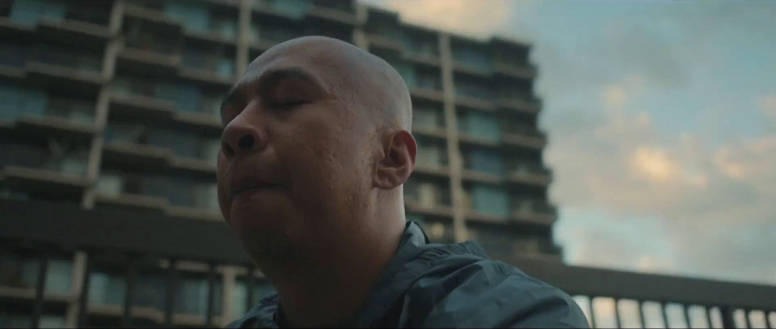 a man with his eyes closed standing in front of a tall building