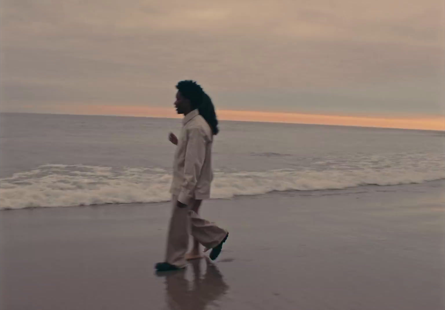 a man walking along a beach next to the ocean