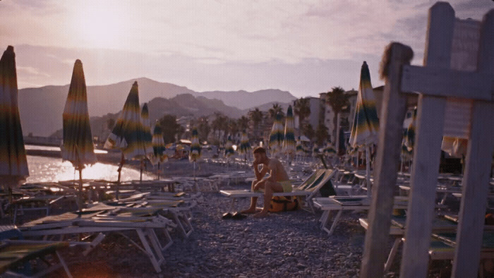 a man sitting on a beach next to a bunch of lawn chairs