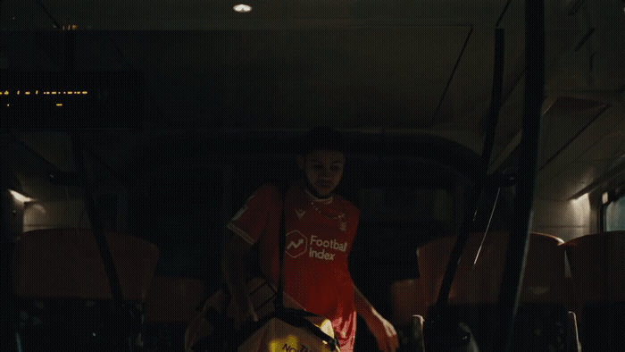 a man in a red shirt standing next to a bus