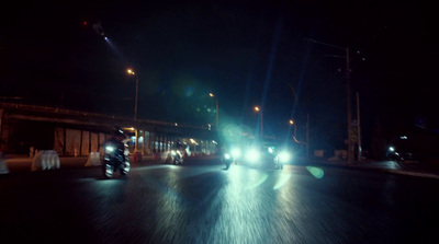 a couple of motorcycles driving down a street at night