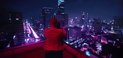 a woman in a red jacket looking out over a city at night