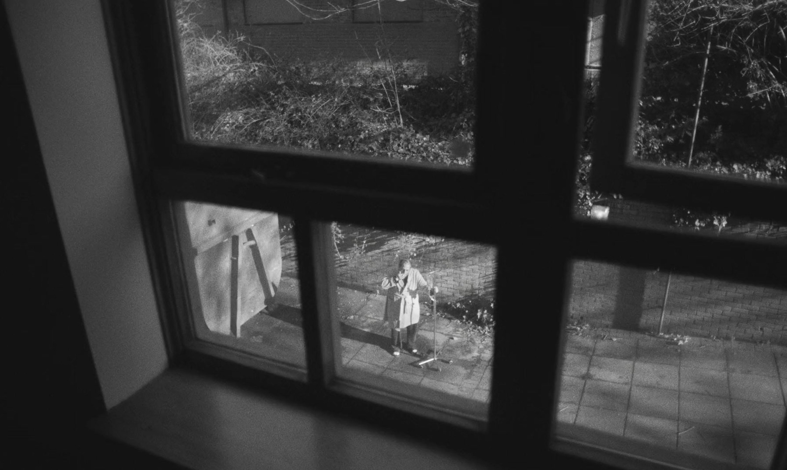 a black and white photo of a person looking out a window