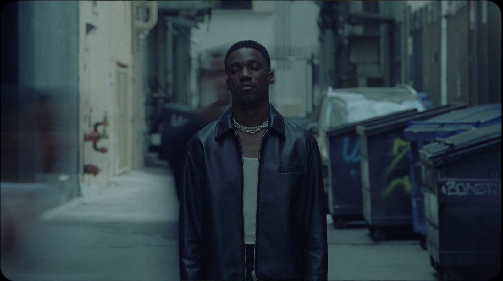 a man in a black jacket standing on a sidewalk