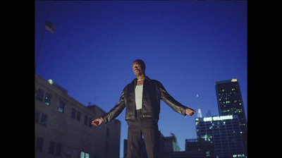 a man in a leather jacket standing in front of a building