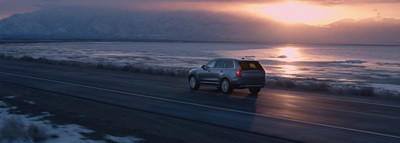 a car driving down a road next to a body of water