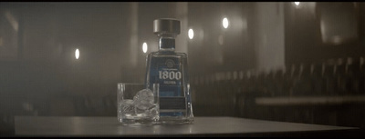 a bottle of alcohol sitting on top of a table next to a glass