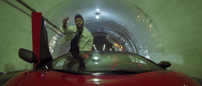 a man standing on top of a red car in a tunnel