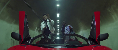 two men standing next to a red sports car