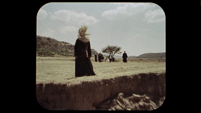 a group of people standing on top of a dry grass field