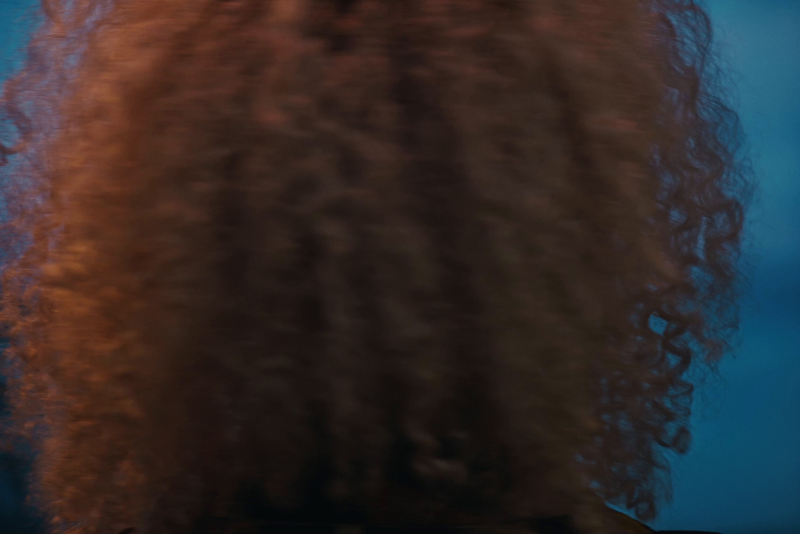 the back of a woman's head with long, curly hair