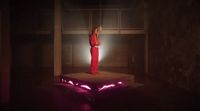 a woman in a red jumpsuit standing on a platform