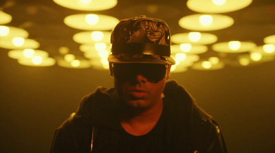 a man wearing a hat and sunglasses in a dark room