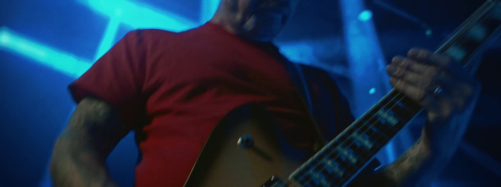 a man in a red shirt playing a guitar