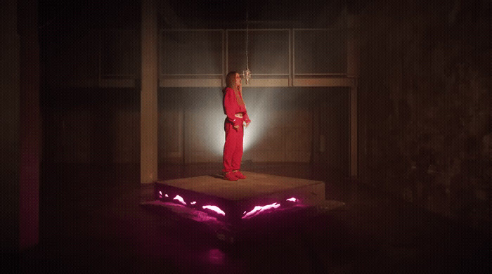 a woman in a red jumpsuit standing on a platform