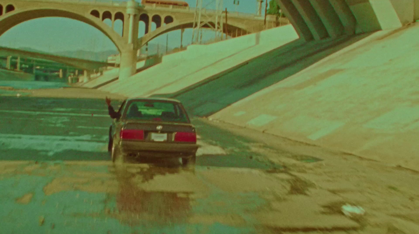 a car driving through a flooded street under a bridge