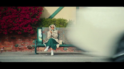 a woman is sitting on a green bench