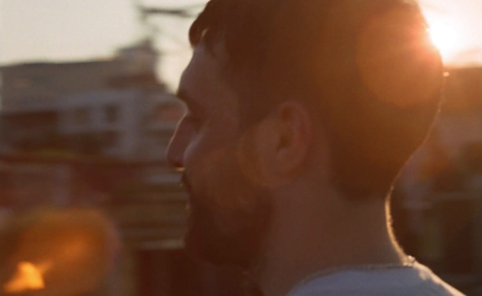 a man standing in front of a building with the sun behind him