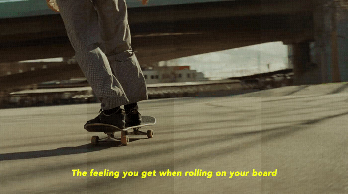 a man riding a skateboard down a street next to a bridge