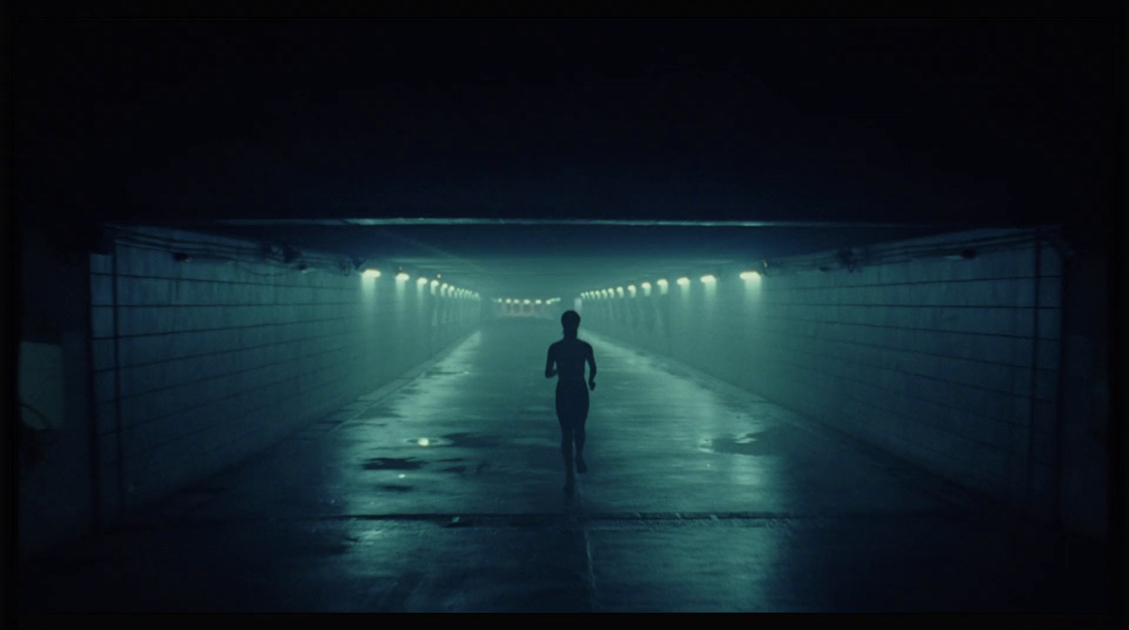 a man walking down a tunnel in the dark