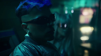 a man with blue hair and sunglasses in a dark room