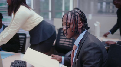 a man with dreadlocks sitting at a desk