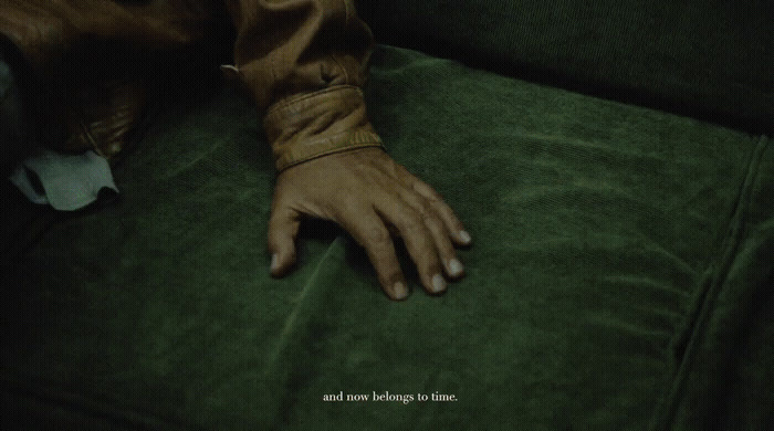 a person's hand resting on a green couch