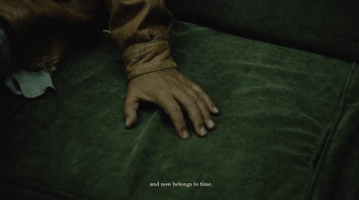 a person's hand resting on a green couch