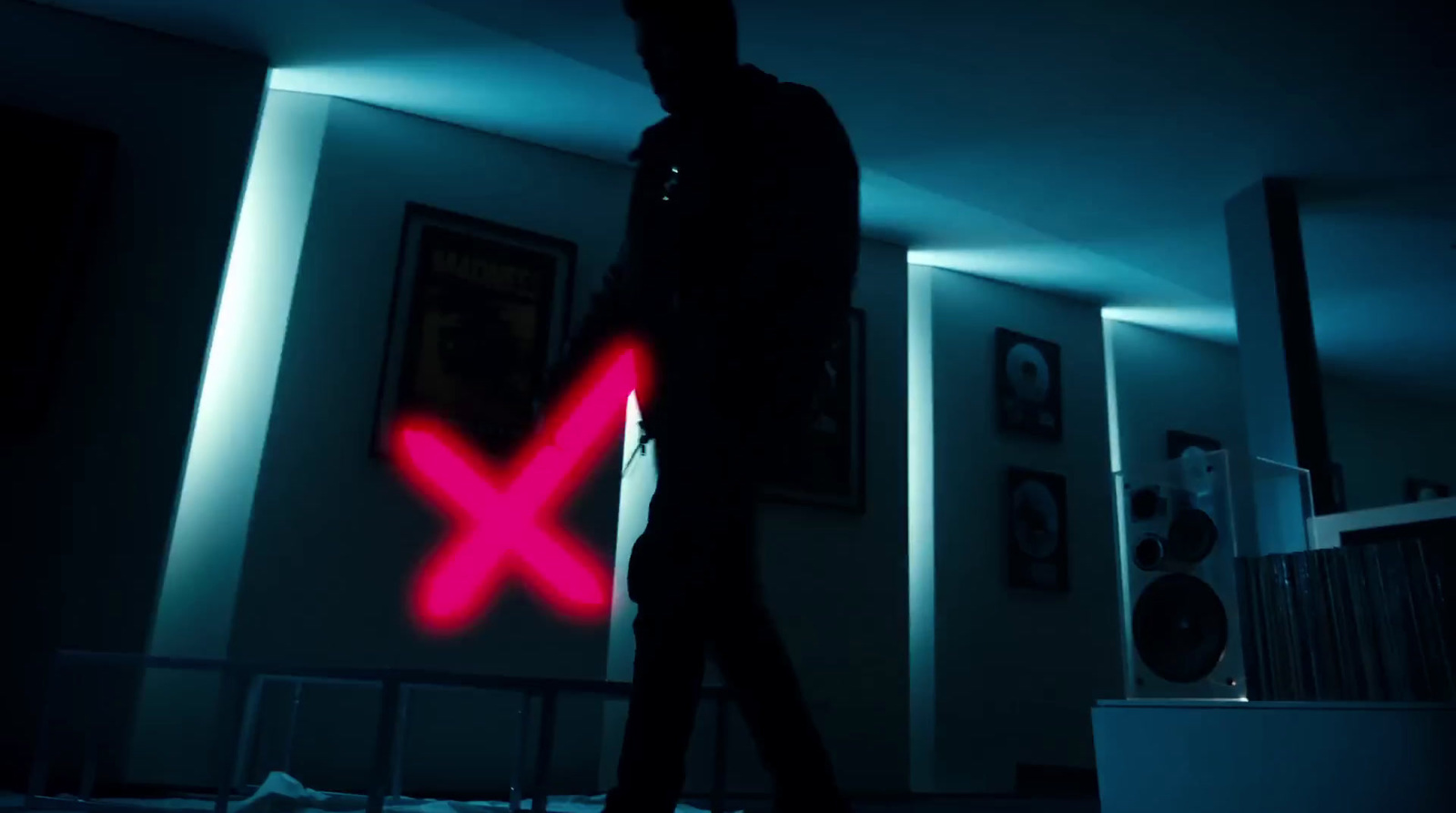 a man walking in a dark room with a red x on it