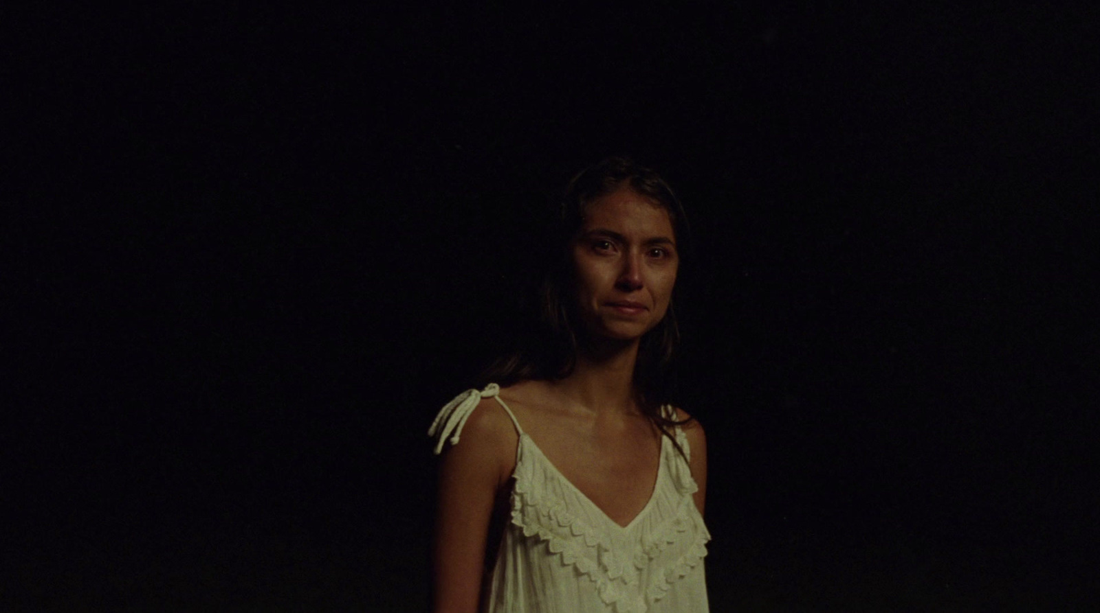 a woman standing in the dark with a frisbee in her hand