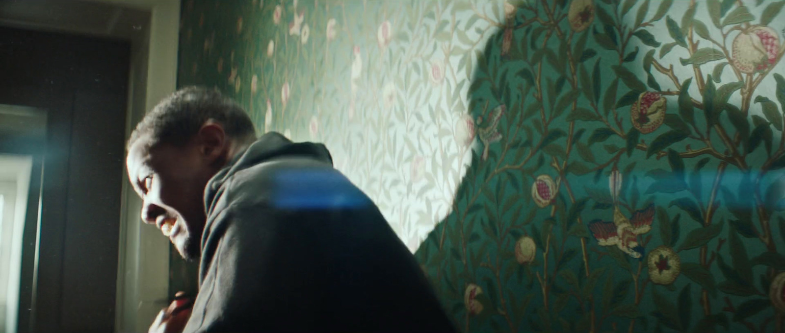 a man standing in front of a wall covered in wallpaper