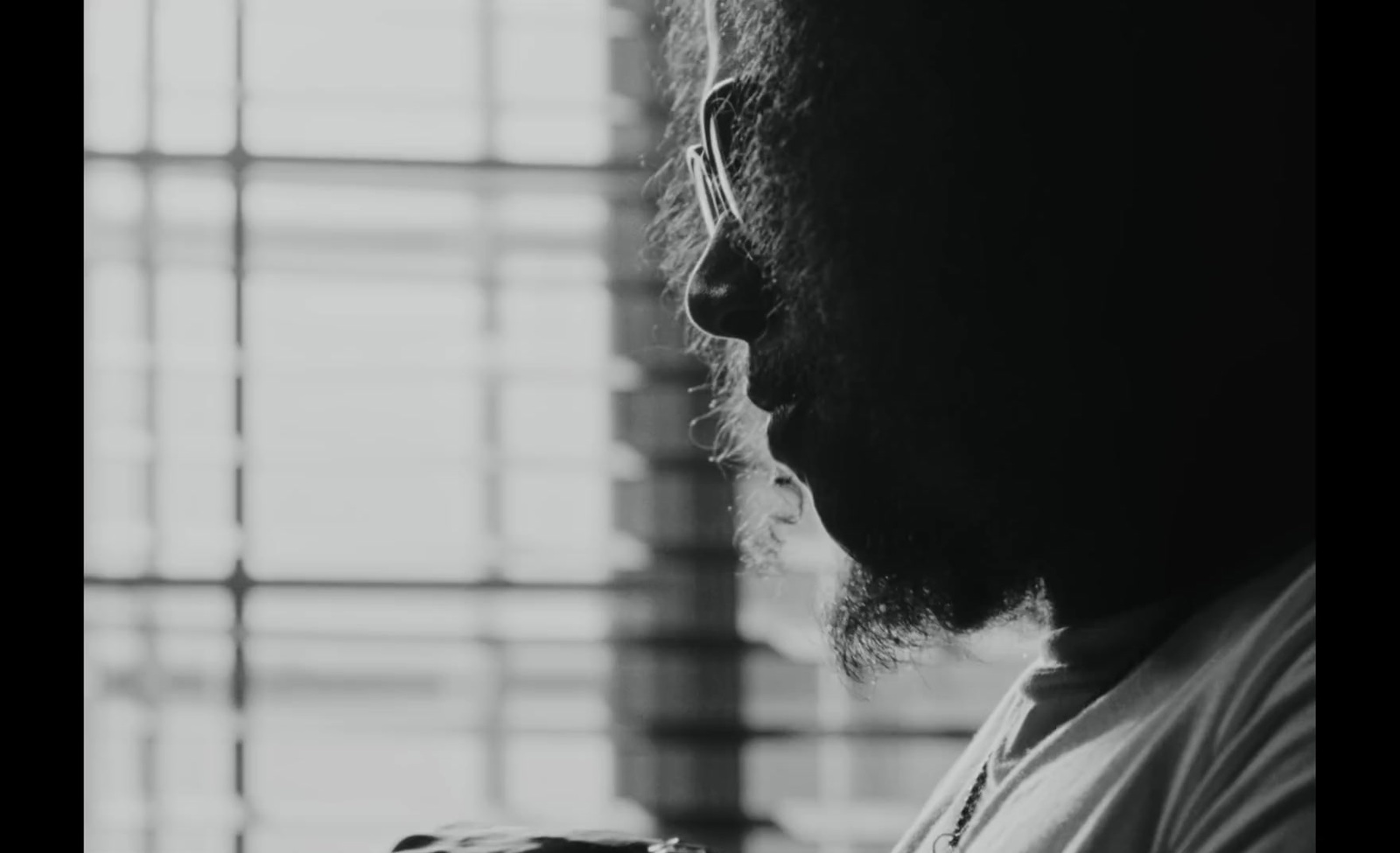 a black and white photo of a man looking out a window