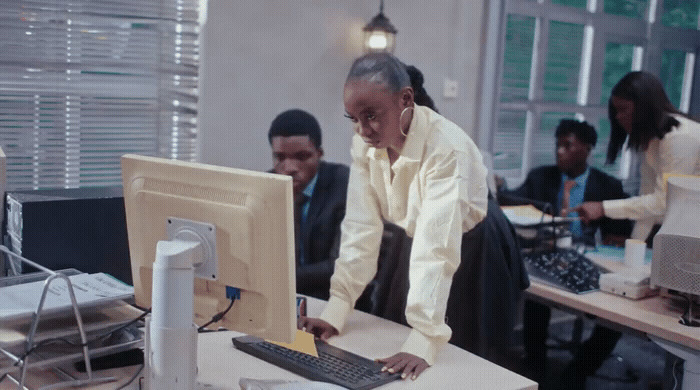 a woman standing at a desk in front of a computer