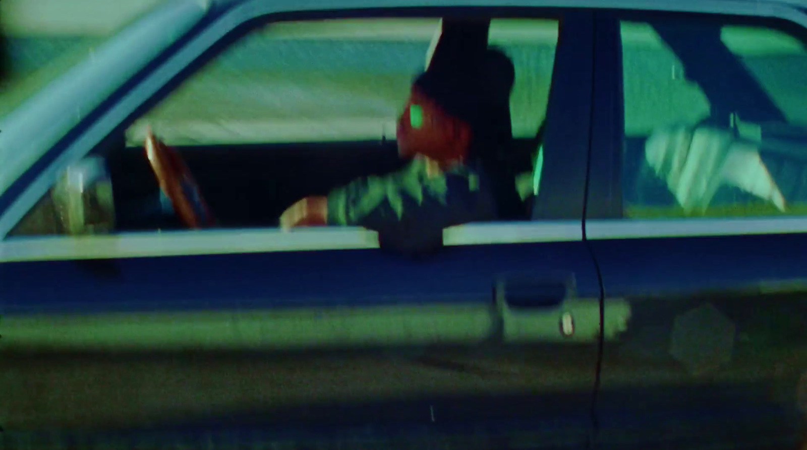 a man sitting in the driver's seat of a blue car