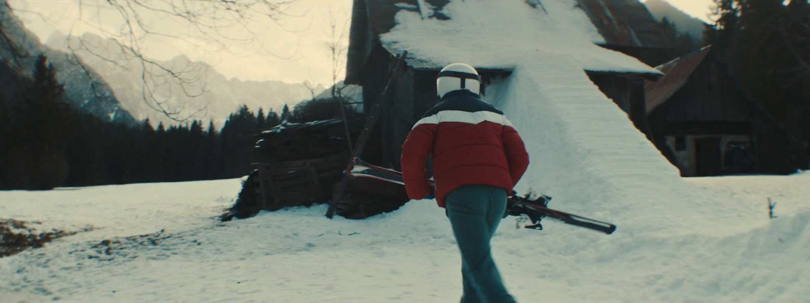 a person walking in the snow carrying skis