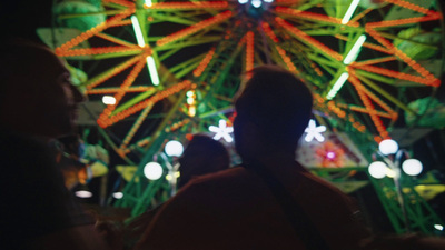 a ferris wheel lit up at night with people looking on