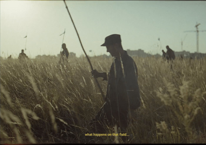 a man standing in a field holding a fishing pole