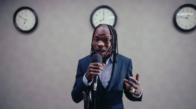 a man holding a microphone in front of three clocks