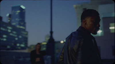 a man in a leather jacket standing in front of a building