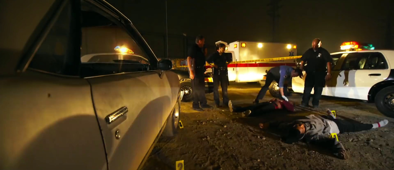 a person laying on the ground next to a police car